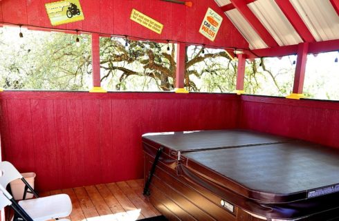 Large hot tub in red outdoor building with open windows