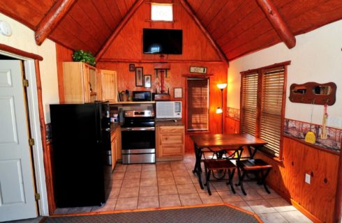 Cabin interior kitchen with A-frame roof, table with four chairs and tiled floor