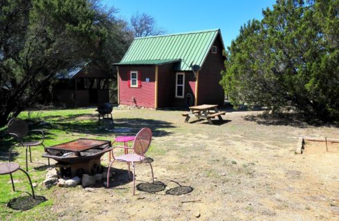 Outdoor backyard behind a cabin with fire pit, picnic table and horseshoe pit