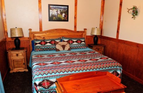 Cabin bedroom with queen bed in aztec style quilt with side tables and lamps