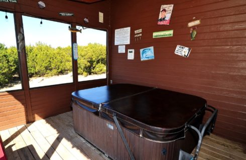 Large hot tub in brown exterior building with open air windows