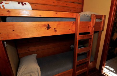 Bunk beds in a hallway of a cabin with doorway into a bathroom