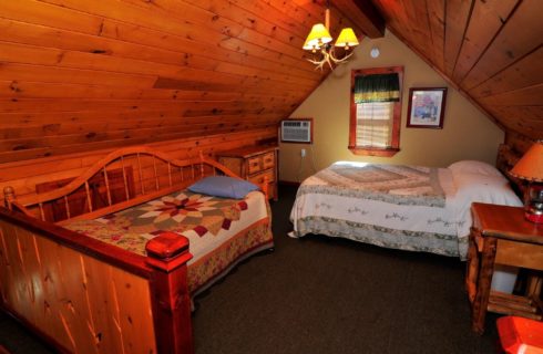 Loft bedroom with a-frame roof, queen bed, day bed and side table with lamp