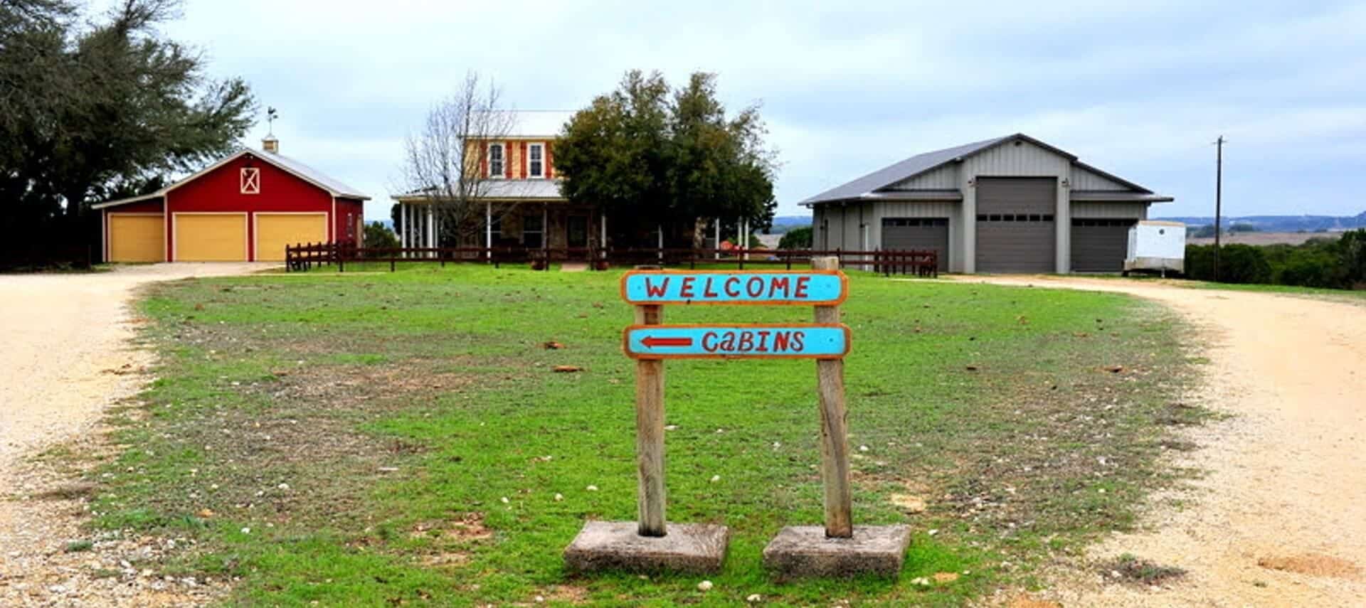 Sign at the end of a driveway of a home saying "Welcome" and an arrow pointing the way to cabins