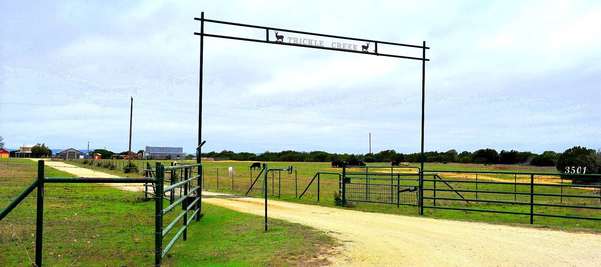 Tall sign gate at the beginning of a long driveway to a farm property